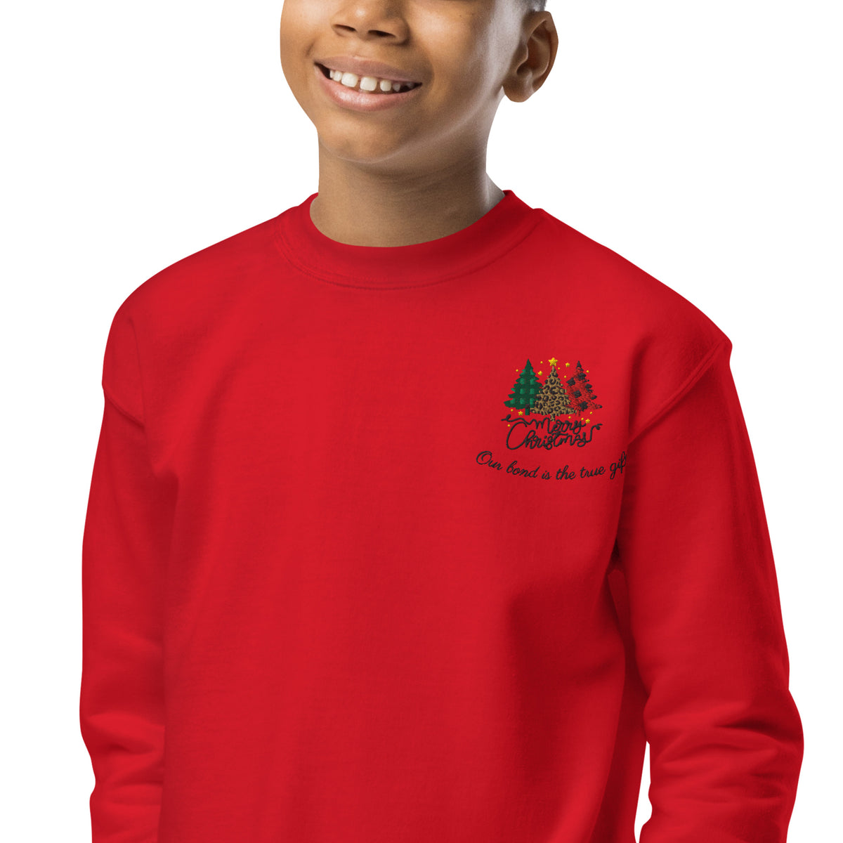 Close-up of embroidered Christmas trees and Merry Christmas script on red kids sweatshirt